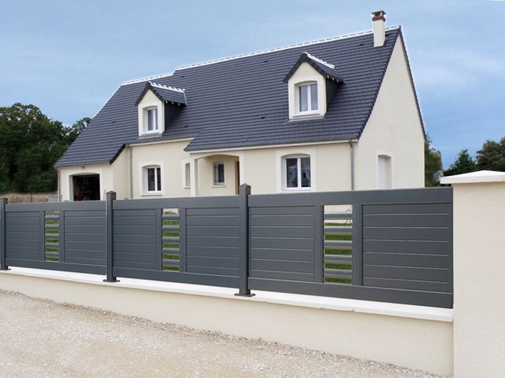 Une maison blanche avec une clôture grise devant elle